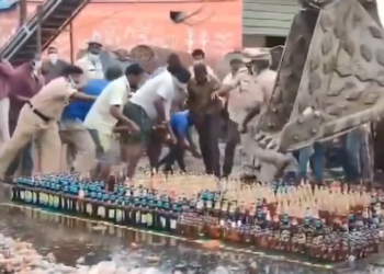 আচৰিত! আৰক্ষীৰ সন্মুখতেই সুৰাৰ বটলক লৈ টনা-আঁজোৰা